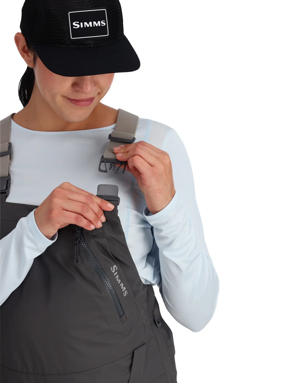 Person wearing a black cap and gray overalls with 'Simms' branding on a white background