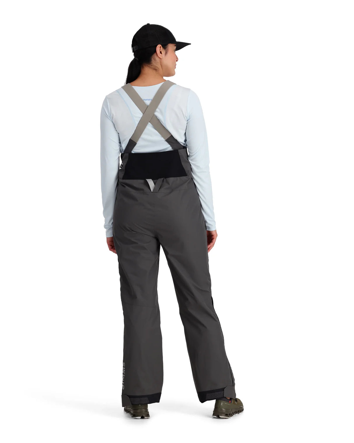 Person wearing gray bib overalls on a white background