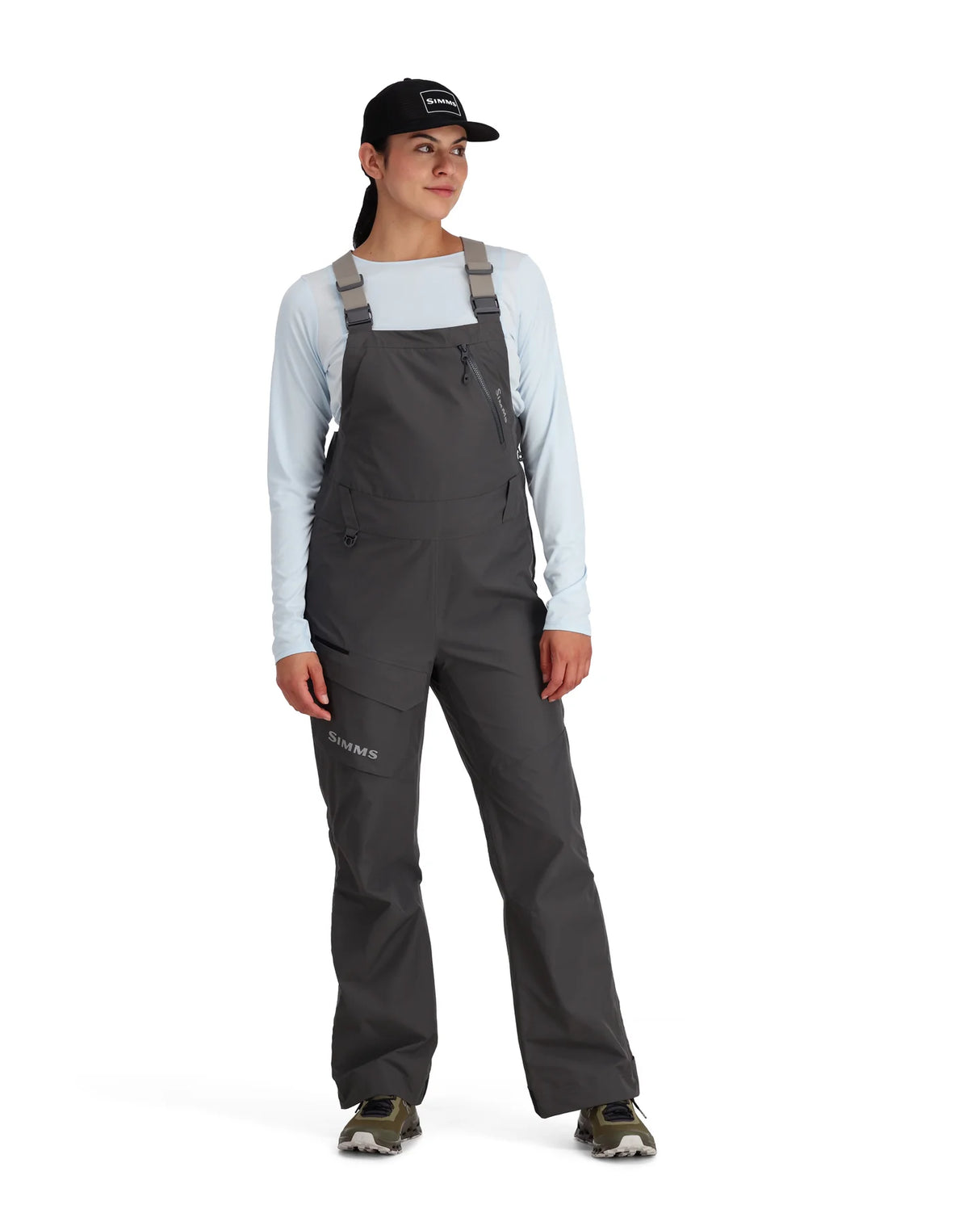 Person wearing a gray bib overalls and cap on a white background