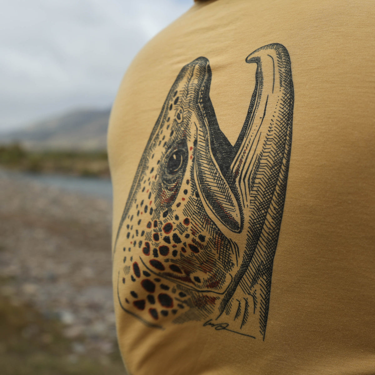 dark tan sun hoody with a brown trout head on the back on the buckskin merino breeze sun hoody by repyourwater close up