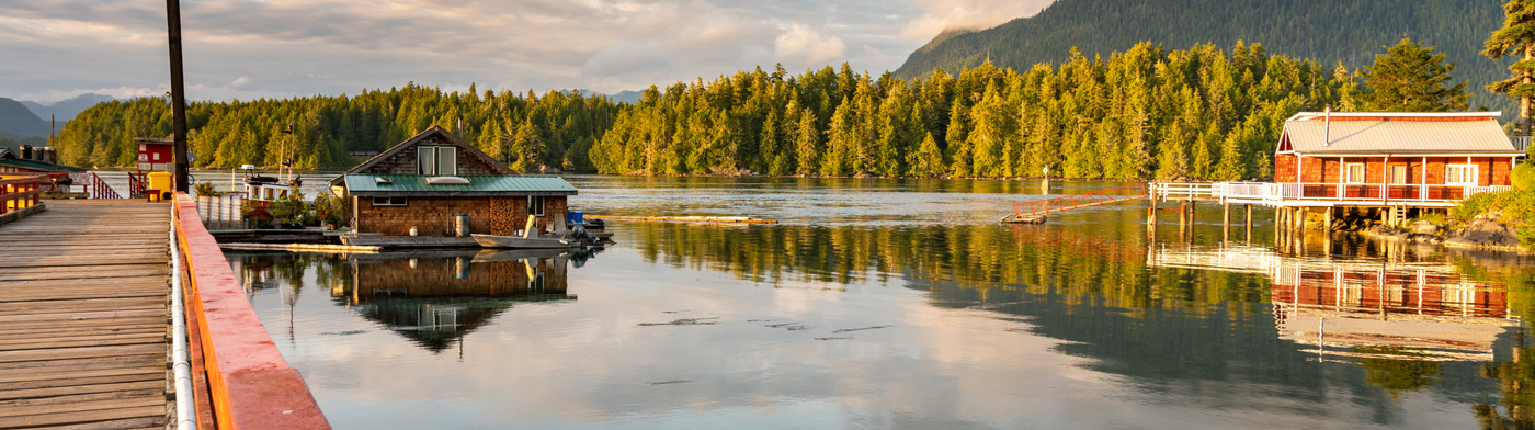Panoramic view of a lake with houses on stilts and a forested background.
