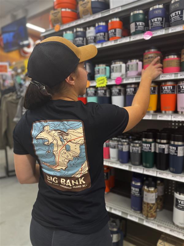 Person shopping in a store aisle with shelves stocked with colorful tumblers.