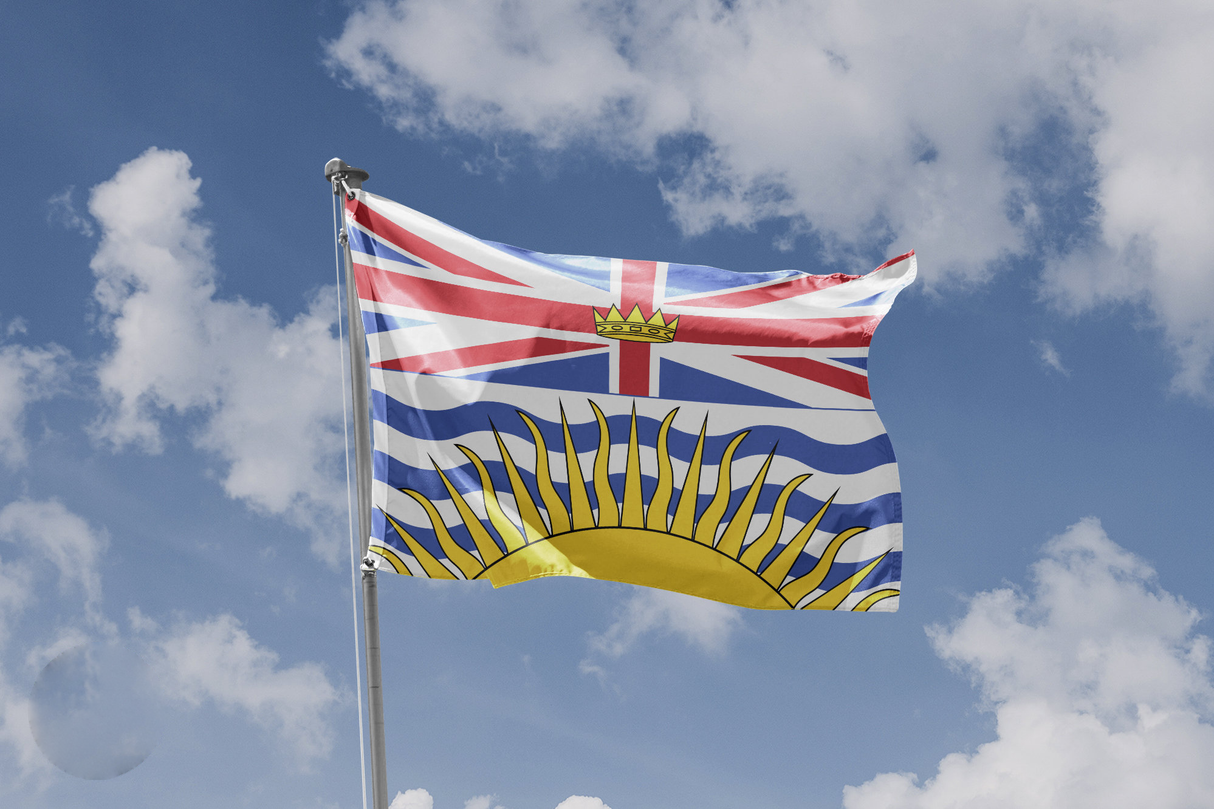British Columbia flag flying on a flagpole against blue sky with clouds