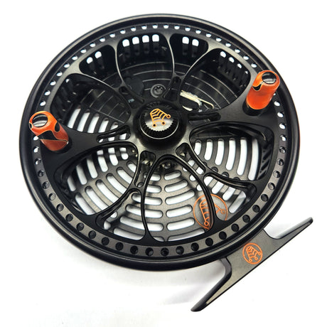 Black and orange fishing reel on a white background