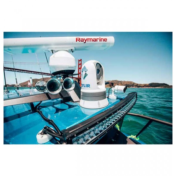 A Raymarine radar system mounted on a boat deck, featuring a white radar dome and a FLIR camera, set against a background of blue water and sky.
