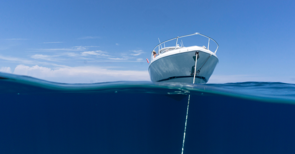 Boat anchored securely in calm blue water with anchor line visible below the surface – demonstrating safe anchoring with an Anchor Buddy system.