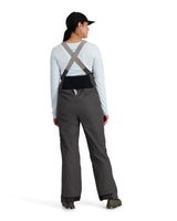 Person wearing gray bib overalls on a white background