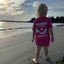 Child wearing a pink t-shirt with 'Harbour Chandler' branding on a beach. - Pink - XS