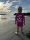 Child wearing a pink t-shirt with 'Harbour Chandler' branding on a beach. - Pink - XS