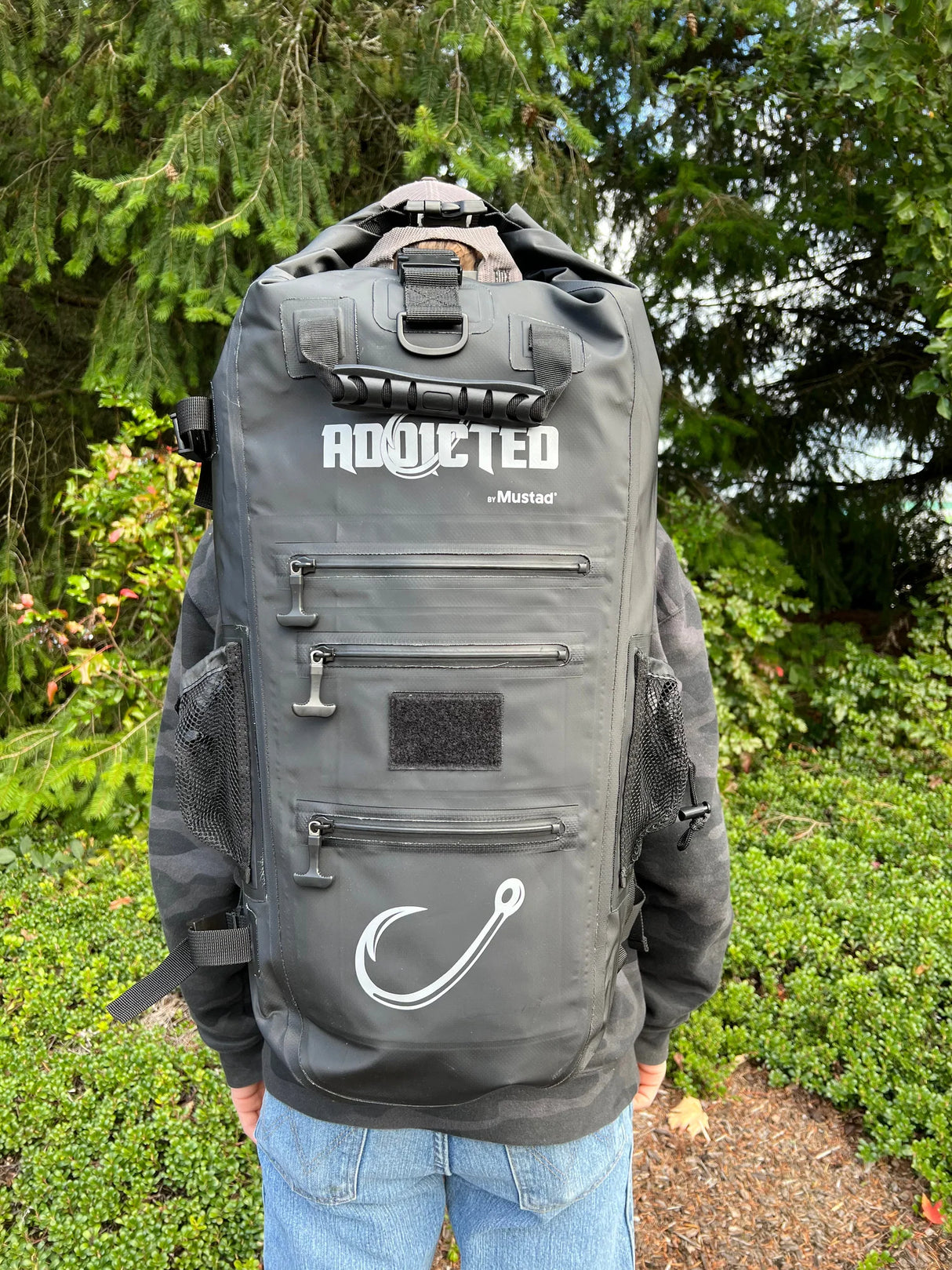 Person wearing a gray backpack with 'Addicted' branding outdoors.