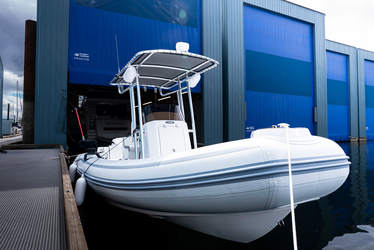 AB Inflatables 21 Oceanus VST tied up at a dock in front of blue boathouse doors