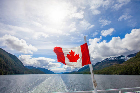 Canadian flag flying from a boat on a scenic mountain waterway