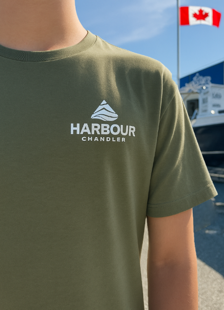 Person wearing a green t-shirt with 'Harbour Chandler' logo, with a Canadian flag and boat in the background. - Army Green - S