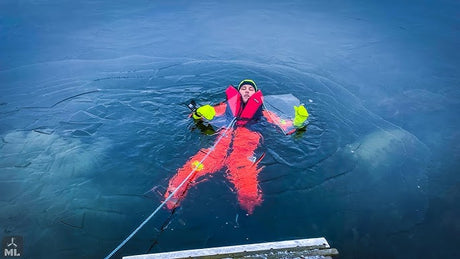 Person wearing red flotation suit on open water during cold weather marine conditions