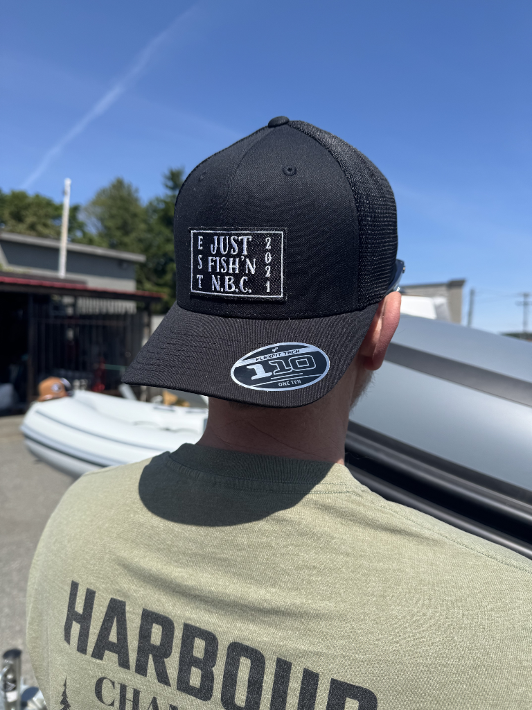 Person wearing a black cap with text and a green shirt with 'Harbour' text, outdoors.