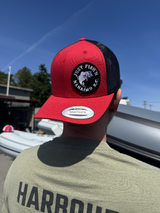 Person wearing a red and black cap with a logo, standing outdoors.