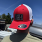Red and white cap with a patch on a person against a blue sky.