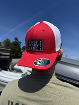Red and white cap with a patch on a person against a blue sky.