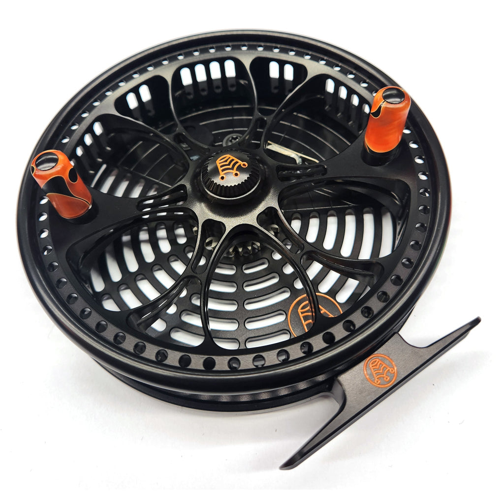 Black fly fishing reel with orange accents on a white background