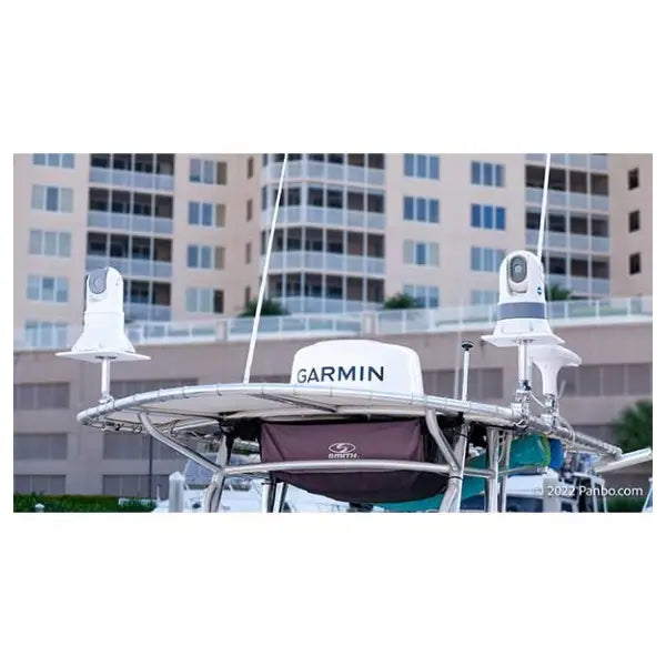 A Garmin radar dome and two white radar antennas mounted on a boat's T-top frame, with a marina building in the background.
