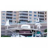 A Garmin radar dome and two white radar antennas mounted on a boat's T-top frame, with a marina building in the background.