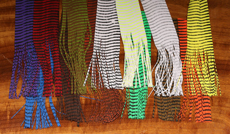 Collection of colorful scarves with fringe on a wooden surface
